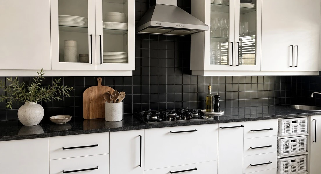 After — Dated timber cabinetry hand-painted in warm white, slim black handles and a square black-tile backsplash. Existing granite retained — a full change of character with the original kitchen still in place.